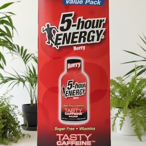May include: A red and black 5-hour ENERGY Berry flavor 10-count value pack. The box features the product name, a silhouette of a person, and the words "Tasty Caffeine". The box also states that the product is sugar-free and contains vitamins.