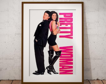 May include: A framed poster featuring the movie title "PRETTY WOMAN" in pink capital letters. The poster shows a man in a black suit and a woman in a pink top and black skirt, leaning back-to-back. The woman wears black thigh-high boots.