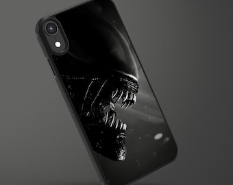 May include: Black and white phone case featuring a detailed image of the Alien creature's head. The design showcases the creature's sharp teeth and textured skin, set against a dark background. The case is angled, showing the phone's camera.