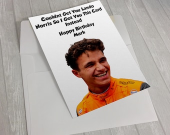 May include: A white greeting card with a photo of a smiling man in an orange racing suit. The card reads "Couldnt Get You Lando Norris So I Got You This Card Instead Happy Birthday Mark."