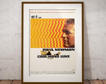 May include: Framed vintage movie poster for "Cool Hand Luke" featuring Paul Newman. The poster has a yellow and orange background with a profile of Newman's face. The title and credits are at the bottom.