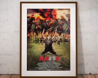 May include: A framed movie poster for the film "Platoon." The poster features a central figure kneeling with arms raised against a backdrop of a fiery explosion and palm trees. The title "Platoon" is prominently displayed in red.