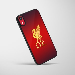Pode incluir: Capa preta para smartphone com fundo gradiente vermelho e preto. Apresenta um emblema dourado do pássaro Liver e as letras "L.F.C." em dourado. A lente da câmera do telefone é visível.