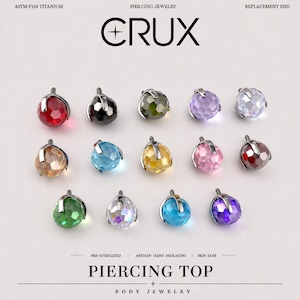 Pode incluir: Uma coleção de catorze pontas de substituição para piercing em titânio ASTM F136 da CRUX. Cada peça apresenta uma pedra preciosa redonda facetada presa por um engaste de garra metálico em várias cores, incluindo vermelho, preto, verde, roxo, azul e transparente.