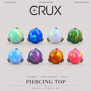 Pode incluir: Oito topos de piercing redondos com pedras iridescentes tipo opala em várias cores, incluindo menta, azul, branco, verde, azul claro, roxo, laranja e rosa, cada um montado numa base de metal escuro com o texto CRUX PIERCING TOP.