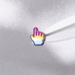 May include: A small metal pin shaped like a computer mouse cursor hand icon. The pin features a gradient finish that transitions from a vibrant pink at the top, through a bright yellow in the middle, to a deep blue at the bottom edge.
