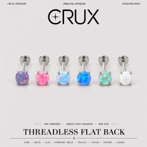 Könnte beinhalten: Sechs gewindelose Piercing-Stecker mit flacher Rückseite und runden, krappengefassten Opalsteinen in Lila, Pink, Hellblau, Dunkelblau, Türkis und Weiß. Der Text CRUX PIERCING JEWELRY PUSH-PIN POST und THREADLESS FLAT BACK ist sichtbar.