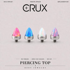 May include: Four teardrop-shaped piercing tops from Crux Jewelry, each featuring a different coloured stone: pink, blue, white, and iridescent purple. Each piece has a metallic base with a threaded post for attachment to body jewellery.