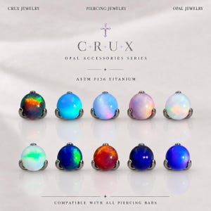 May include: Ten round opal cabochon piercing jewelry attachments arranged in two rows. Each stone is set in a dark metal base. Text reads: CRUX JEWELRY, PIERCING JEWELRY, OPAL JEWELRY, C+R+U+X, OPAL ACCESSORIES SERIES, ASTM F136 TITANIUM, COMPATIBLE WITH ALL PIERCING BARS.