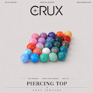 Peut inclure: Une collection de bijoux de piercing ronds et multicolores de style opale disposés en grille. Le texte CRUX PIERCING JEWELRY REPLACEMENT END et PIERCING TOP BODY JEWELRY PRE-STERILIZED ARTISAN HAND PACKAGING SKIN SAFE est visible sur le fond clair.