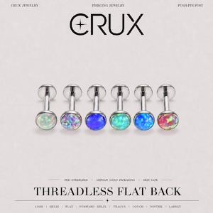 May include: Six silver-toned threadless flat back piercing studs with circular opal-style cabochons in white, iridescent, deep blue, light green, bright blue, and pink. The text CRUX PIERCING JEWELRY PUSH-PIN POST THREADLESS FLAT BACK is visible.