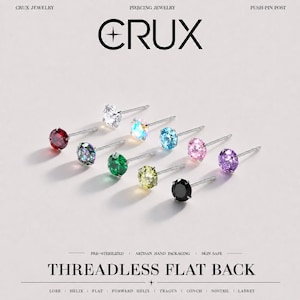 May include: A collection of nine threadless flat back piercing studs from Crux Jewelry, each featuring a round faceted gemstone in colours including red, clear, iridescent, green, yellow, blue, pink, purple, and black on a silver-tone post.