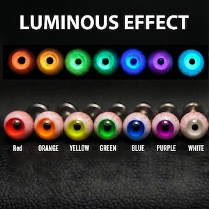 May include: A set of seven round eye-shaped studs with a luminous effect. The top row shows the studs glowing in red, orange, yellow, green, blue, purple, and white. The bottom row displays the studs in daylight with corresponding color labels.