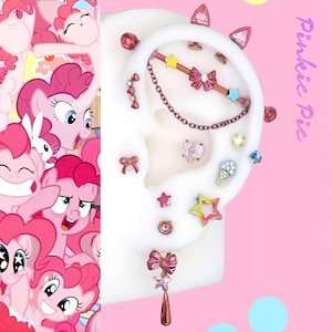 Può includere: Un'esposizione di piercing per le orecchie rosa e oro rosa, tra cui borchie, una catena e un bilanciere. I piercing presentano forme a stella, fiocco e cuore, con uno sfondo rosa e il testo "Pinkie Pie".