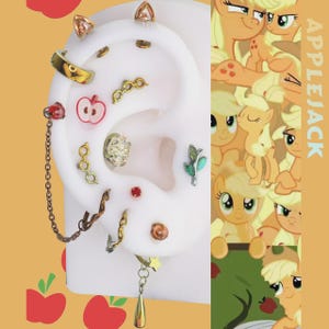 May include: A collection of earrings displayed on a white ear model. The earrings feature various designs, including an apple, a chain, and geometric shapes. The background features a cartoon character and the word "APPLEJACK".