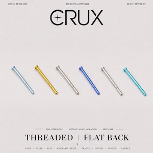 May include: Six straight piercing jewelry posts in various metallic colors including light blue, gold, silver, dark blue, and turquoise. The text CRUX JEWELRY PIERCING JEWELRY BODY JEWELRY and THREADED FLAT BACK LOBE HELIX FLAT FORWARD HELIX TRAGUS CONCH NOSTRIL LABRET is visible.