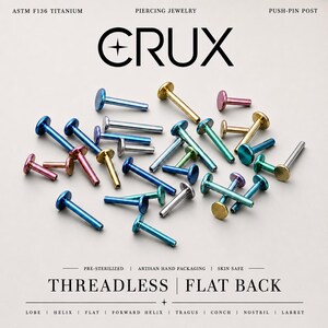 May include: A collection of ASTM F136 titanium push-pin piercing jewelry with flat backs. The pieces feature various metallic colors including blue, gold, pink, and silver. Text on the image reads CRUX, THREADLESS | FLAT BACK, and other details.
