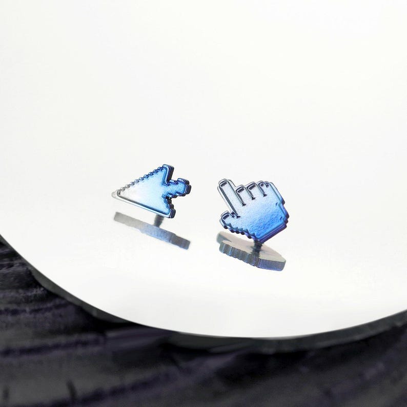 May include: A pair of stud earrings featuring a blue metallic finish. One earring is shaped like a standard computer mouse arrow cursor, and the other earring is shaped like a computer mouse hand pointer icon, both with a pixelated design.