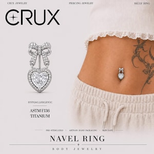 May include: A silver-toned navel ring featuring a bow design at the top and a heart-shaped pendant at the bottom, both encrusted with clear stones. The jewelry is labeled as ASTM F136 titanium, hypoallergenic, and pre-sterilized by Crux Jewelry.