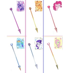 May include: Six colorful body jewelry pieces with cartoon pony illustrations. Each piece has a long, thin shaft with a pointed end and a decorative top. The shafts are in various colors, including pink, yellow, and blue.