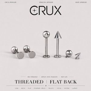 May include: A collection of silver-toned metal body jewelry featuring threaded flat back posts. The set includes pieces with spherical and conical ends, displayed alongside separate screw-on attachments. Text reads CRUX, THREADED, and FLAT BACK.