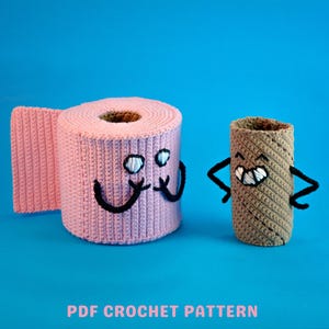 Peut inclure: Un rouleau de papier toilette rose crocheté avec un visage souriant et des bras noirs se tient à côté d'un tube de papier toilette crocheté marron avec un visage souriant et des bras noirs. Le texte "PDF CROCHET PATTERN" est en bas.
