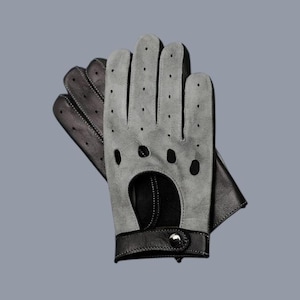 Pode incluir: Um par de luvas de condução cinzentas com detalhes em couro preto. As luvas apresentam um design perfurado nas costas e uma correia de pulso com fecho de botão. Estas luvas são projetadas para conduzir e oferecem um visual elegante.
