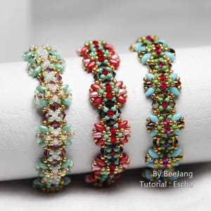 May include: Three beaded bracelets with intricate floral patterns. The bracelets feature a variety of colors, including red, pink, green, and gold. The bracelets are displayed on a white cylindrical surface.