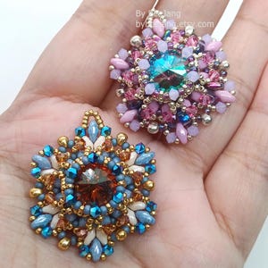 Ceres pendants in two colors. One is in copper, blue and beige. The other is in pink, purple and silver.