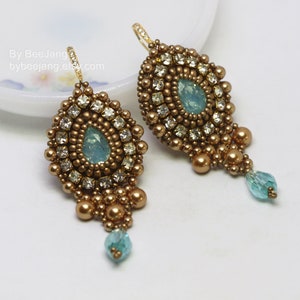 May include: A pair of gold tone dangle earrings with teardrop shaped blue crystals and gold beads.