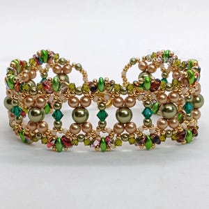 Puede incluir: Una pulsera de cuentas con un marco de metal dorado, cuentas verde oliva, marr&oacute;n claro y verde. La pulsera tiene un dise&ntilde;o sim&eacute;trico con cuentas redondas y facetadas, creando un aspecto texturizado.