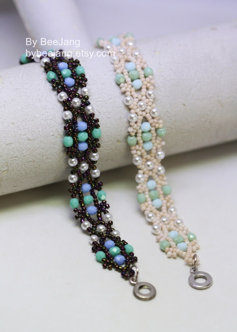 May include: Two beaded bracelets with a white background. The bracelet on the left has brown, blue, and green beads. The bracelet on the right has white, blue, and green beads. Both bracelets have silver clasps.