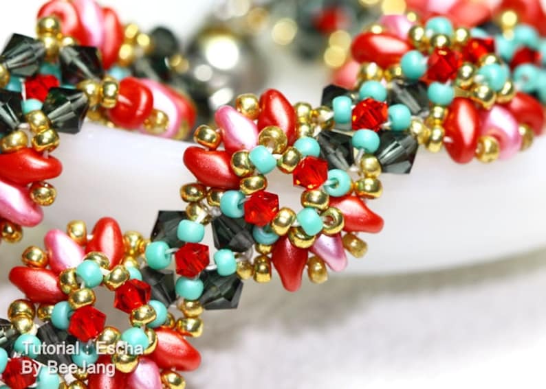 May include: Close-up of a beaded bracelet with a floral design. The bracelet features red, pink, and turquoise beads, accented with gold and dark gray crystal beads. The text "Tutorial: Escha By BeeJang" is visible.