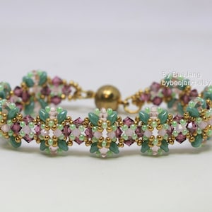 May include: A beaded bracelet featuring a floral design with green, pink, and purple beads. The bracelet has a gold-colored clasp and accents. The text "By BeeJang bybeejang.etsy.com" is visible on the right side.