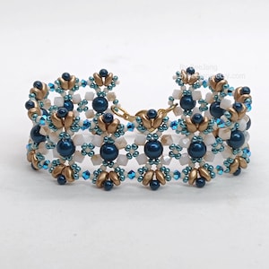 May include: A beaded bracelet with a repeating pattern of navy blue, gold, and white beads. The bracelet has a gold-coloured clasp and is designed with a floral motif. The beads are arranged in a symmetrical design.
