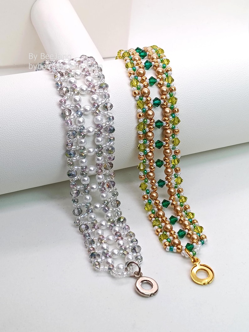Two wide, handcrafted beaded cuff bracelets are draped over a white stand, showcasing an intricate Right Angle Weave lattice design. Each piece is woven with faceted bicone crystals, smooth round pearls, and seed beads, secured with a metallic toggle clasp.

    Left: Clear crystals and white pearls with a silver clasp.
    Right: Emerald and olive green crystals with gold-toned pearls and a gold clasp.