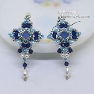 May include: A pair of blue and white beaded earrings with a teardrop-shaped pearl dangle. The earrings are in the shape of a starburst with a blue gemstone in the centre.