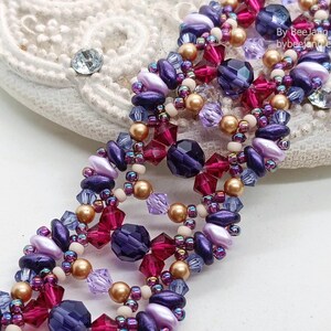 Puede incluir: Una pulsera de cuentas con un dise&ntilde;o complejo, con cuentas moradas, rosas y doradas. La pulsera tiene una construcci&oacute;n de m&uacute;ltiples hilos con varias formas y tama&ntilde;os de cuentas. Las cuentas est&aacute;n dispuestas en un patr&oacute;n repetitivo, creando un accesorio texturizado.