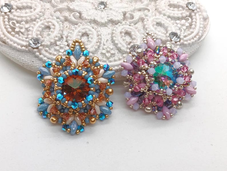 Ceres pendants in two colors. One is in copper, blue and beige. The other is in pink, purple and silver.