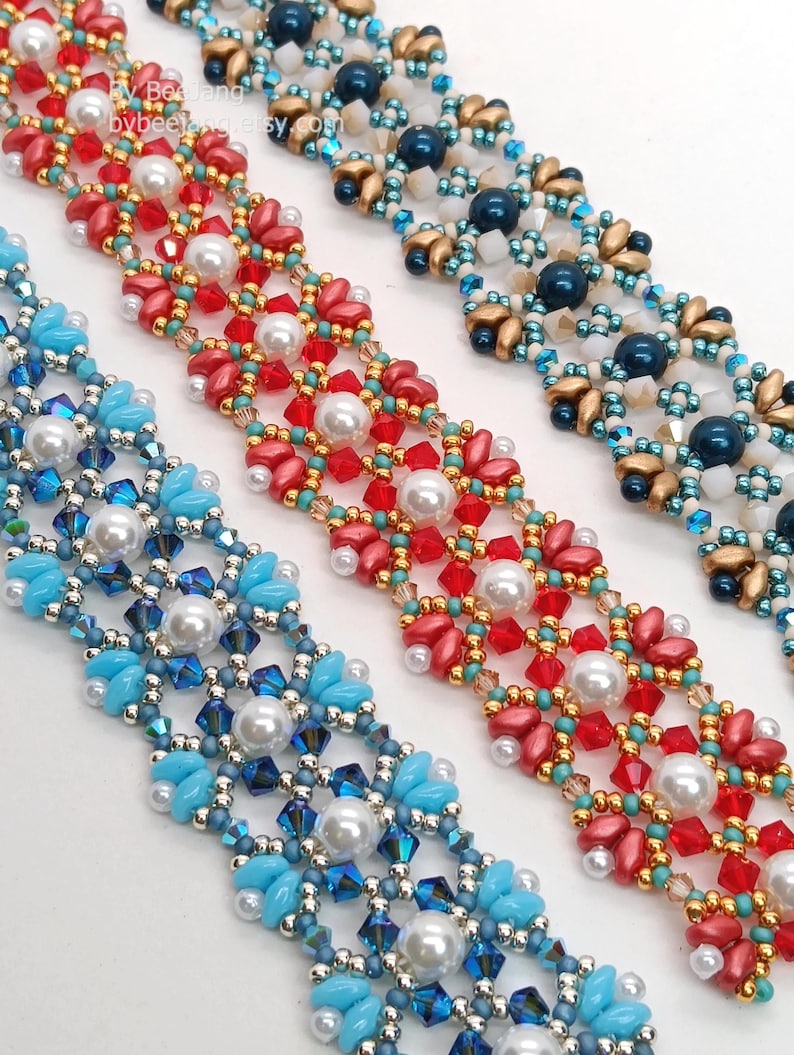 May include: Close-up of three beaded bracelets in red, blue, and gold. Each bracelet features a floral design with pearl accents. The bracelets are made with small beads and crystals, creating a delicate and intricate pattern.