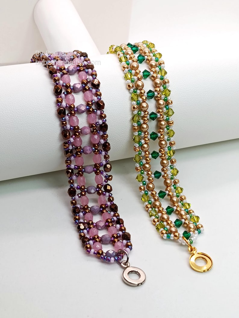 Two wide, handcrafted beaded cuff bracelets are draped over a white cylinder, showcasing an intricate Right Angle Weave lattice design. Each piece is meticulously woven with faceted bicone crystals, round pearls, and seed beads, secured with a metallic toggle clasp.

    Left: Purple and lavender faceted beads accented by dark metallic bronze rounds and a silver clasp.
    Right: Emerald and olive green bicones with gold-toned pearls and a gold clasp.
