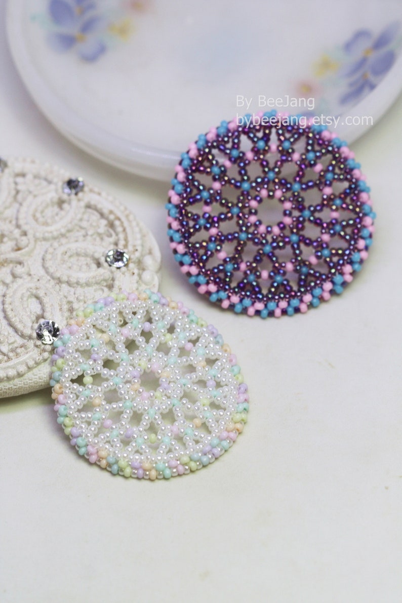 Olwyn wheel pendants in two colors. One is white and mix pastel. The other is purple, pink and blue.