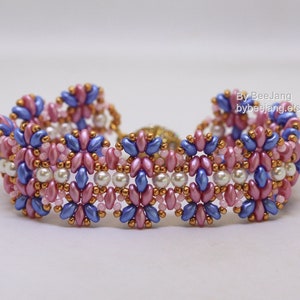 May include: A beaded bracelet featuring a repeating pattern of pink, blue, and gold beads. The bracelet is crafted with small seed beads and larger pearl-like beads.