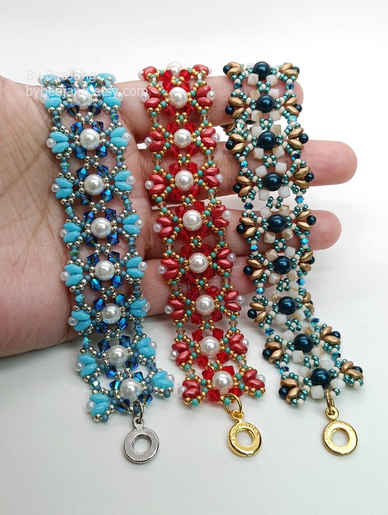 May include: Three beaded bracelets in blue, red, and teal. Each bracelet features a floral design with pearl accents and a metal clasp. The bracelets are handmade and suitable for everyday wear.