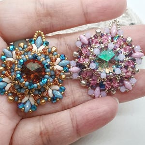 Ceres pendants in two colors. One is in copper, blue and beige. The other is in pink, purple and silver.