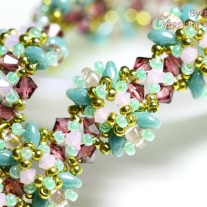 May include: A beaded bracelet featuring a floral design. The bracelet is made with teal, light pink, and purple beads, accented with gold-colored beads. The beads are arranged in a repeating pattern.