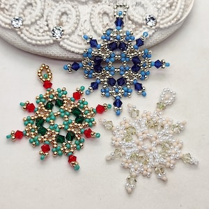May include: Three beaded snowflake ornaments, one blue, one green with red accents, and one white with gold accents.