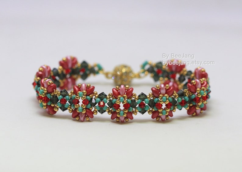 May include: A beaded bracelet featuring a floral design with red, pink, teal, and dark green beads. The bracelet has a gold-colored clasp and accents. The text "By BeeJang bybeejang.etsy.com" is visible.