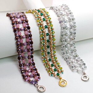 Three wide, handcrafted cuff bracelets are displayed on a white stand, showcasing an intricate Right Angle Weave lattice design. Each piece is meticulously woven with faceted bicone crystals, round pearls, and delicate seed beads, secured with a metallic toggle clasp.

    Left: Purple and lavender crystals with dark metallic bronze accents.
    Center: Emerald and olive green crystals with gold-toned pearls.
    Right: Clear crystals with lustrous white pearls.
