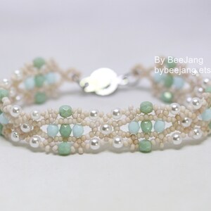 May include: A delicate bracelet with a silver clasp, featuring a multi-strand design of white, cream, and light green beads.